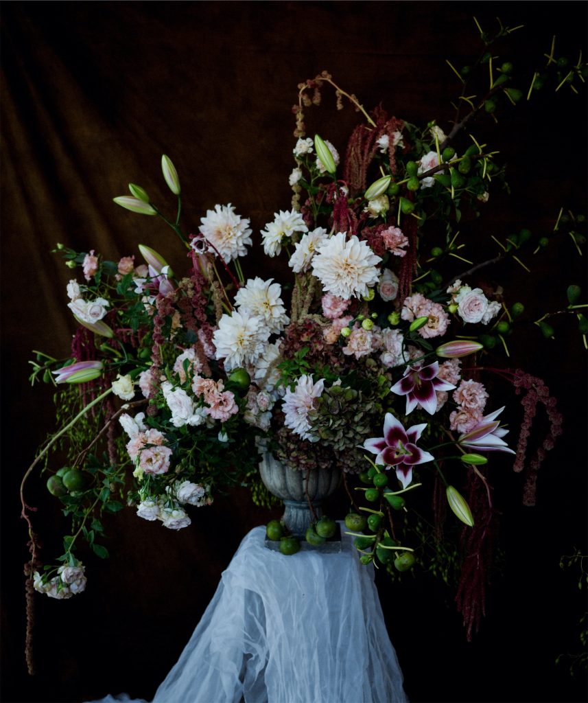 Urn with lush arrangement of flowers featuring dahlias, lilies, lisianthus and roses