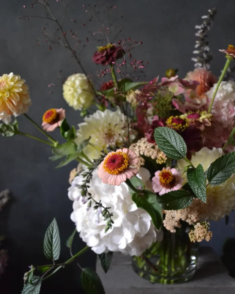 Close up of a vase of flowers, summer seasonal varieties such as zinnia, hydrangea, dahlias, and wildflowers