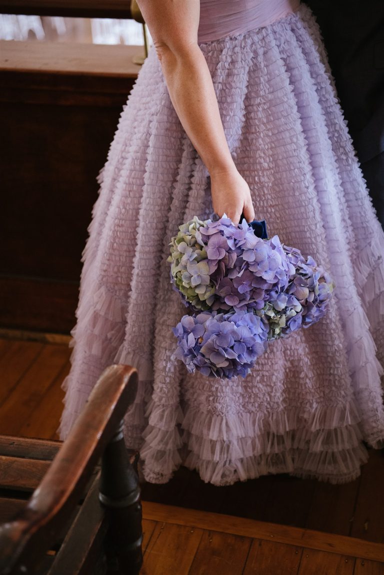 purple and blue hydrangea bouquet, held by a bride in a lilac dress