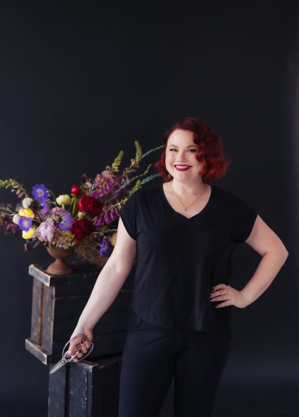 Kris McKee of Kris McKee Floral Design Photo of Kris wearing black in front of a colourful flower arrangement