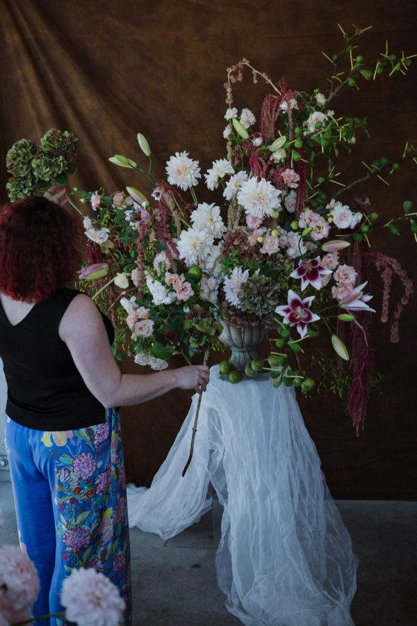 Kris stands in front and to the left of a large urn vase arrangement,